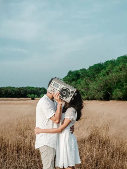 A creative and quirky pre-wedding shot where the couple's kiss is hidden behind a vintage boombox.