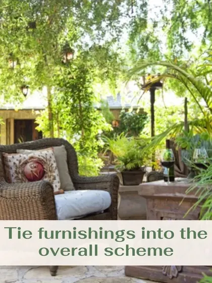 To create a cohesive look, it's important to tie your outdoor furnishings into the overall design scheme. This wicker armchair and side table complement the natural, rustic feel of the stone patio and surrounding greenery.