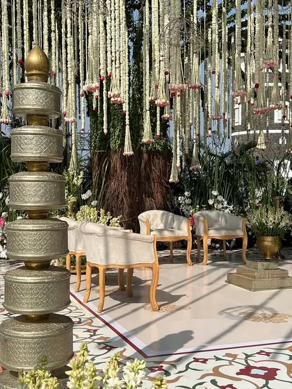 The intricate details of our nature-inspired mandap, featuring stacked brass containers and lush white florals against a custom-printed backdrop.