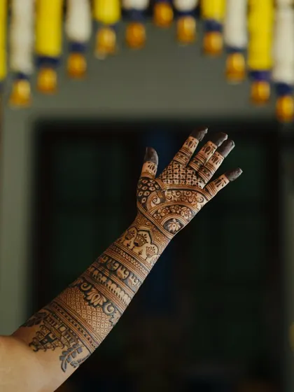 A single arm raised to showcase the full length of the intricate bridal mehendi.
