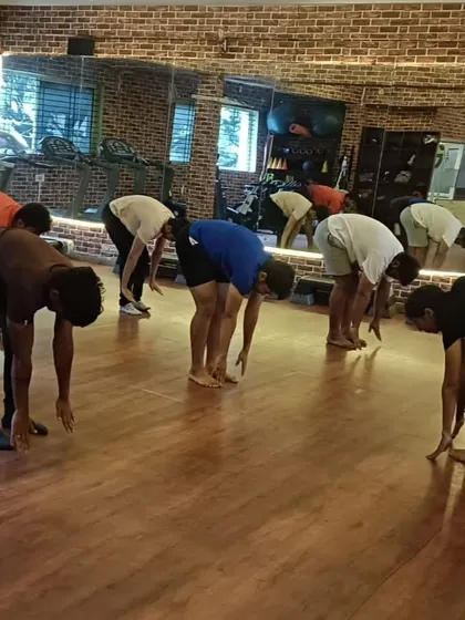 I guide the class through the forward bend, ensuring everyone maintains safe and effective form.