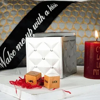 A close-up of some of the items from my naughty gift sets. This includes fun dice with prompts, a "Wake me up with a kiss" sash, and a decorative candle to set the mood.