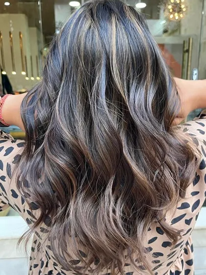 A perfect example of a sun-kissed caramel balayage on a dark base. I hand-painted these highlights to create a seamless, natural-looking blend that adds warmth and dimension. The final style with soft waves really makes the caramel tones pop.