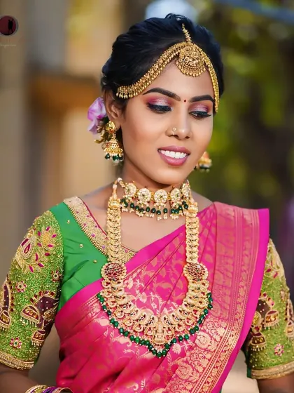 A smiling bride wearing our rental jewellery. This close-up highlights the detailed choker with green stones and the matching long necklace.