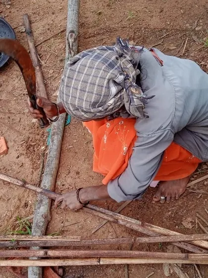A woman mason preparing bamboo strips for a wattle and daub wall. This image highlights the use of traditional tools and techniques passed on through our training programs.