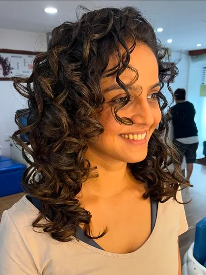This cut enhances the natural bounce and movement of her curly hair.