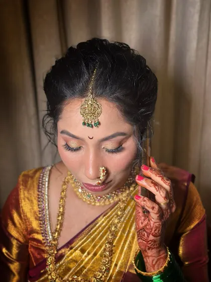 A detailed shot of the Maharashtrian bridal makeup. The focus is on the soft, shimmering eyeshadow, defined eyes, and the way the makeup complements the intricate gold jewellery.