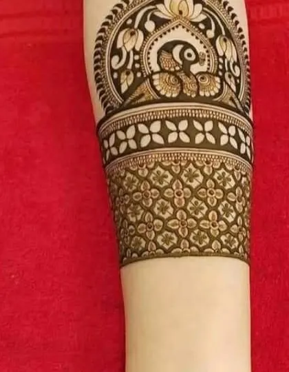 A beautiful cuff-style design for the arm, featuring a peacock surrounded by a lotus mandala. The detail is sharp and clean.