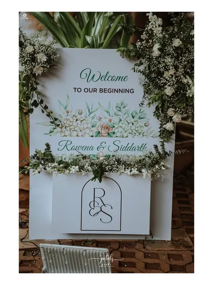 A close-up of the welcome sign for Rowena and Siddarth's wedding, featuring a custom monogram and beautiful watercolor-style floral illustrations.