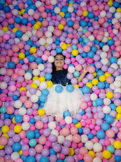 A vibrant and fun photo of a girl having the time of her life in a massive ball pit. This shot is all about capturing the pure, unfiltered joy of being a kid.