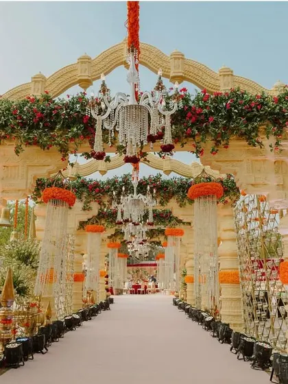 A grand entrance for a traditional event, with arches made of interwoven materials and adorned with marigolds and temple bells.