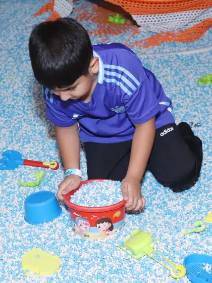 A young boy enjoys some focused playtime in our pellet pit, using buckets and shovels for a fun, sand-like experience without the mess.