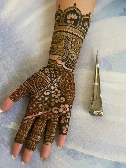 Here you can see one of my intricate wrist and hand designs next to the very cone I used to create it. My cones have a fine tip for precision, allowing for detailed work like the florals and geometric patterns shown here.