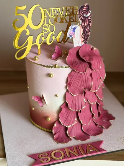 This elegant stunner was made for a queen celebrating her 50th birthday. The design features a flowing gown of hand-shaped petals, blush tones, and a "50 never looked so good" topper.
