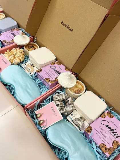 A beautiful flat lay of our bridal shower hampers. These boxes are filled with pampering items like a silk eye mask, a scented candle, gourmet cookies, and pretty accessories to thank your guests for celebrating with you.