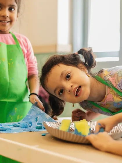 Smiles and splashes of color! Two friends share a laugh in their art class, showing the social and creative fun that happens in our workshops.