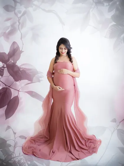 A soft and artistic portrait. The mom-to-be is framed by a beautiful floral overlay, her dusty pink gown creating a romantic and dreamy look.