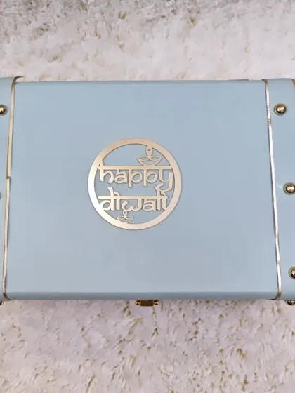 A clean shot of the elegant light blue trunk box with a custom 'Happy Diwali' logo. This reusable box is a gift in itself and adds a touch of luxury.