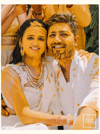 A happy portrait of the couple covered in Haldi paste, smiling for the camera. This image perfectly encapsulates the joyful and messy fun of the ceremony.