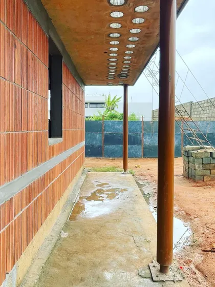 The exterior of the 'Vault & Wall' house, showing the hollow clay block walls and a unique concrete ceiling with circular cutouts.