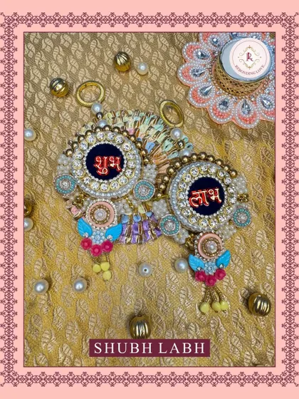 This flat-lay shows our handcrafted Shubh Laabh hangings against a golden brocade fabric. The design features a deep blue center with intricate pearl and bead work, carrying love, light, and luck.