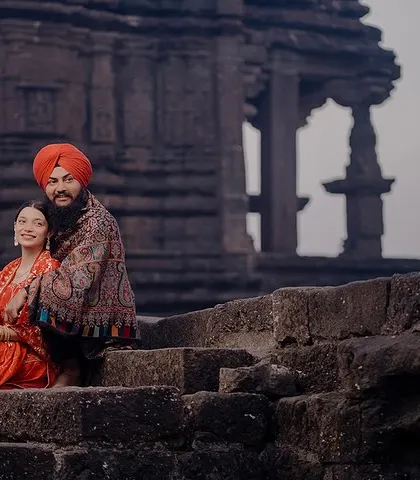 Preet and Gurleen sit together on the ancient stone steps of a temple ruin. The historic setting and their traditional attire create a timeless and powerful image.