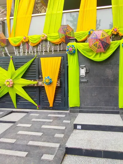 A unique gate decoration using lime green and yellow drapes in star shapes and cone styles for a modern, artistic touch.