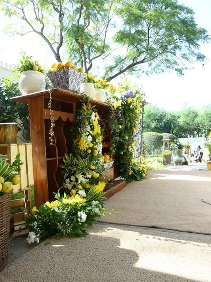 A beautiful garden pathway at a Rajasthan wedding, lined with rustic wooden furniture and lush floral arrangements.