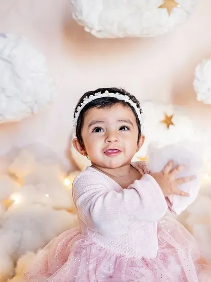 Another sweet moment from our "above the clouds" themed shoot. The soft textures and twinkling lights create a truly magical atmosphere for a first birthday portrait.