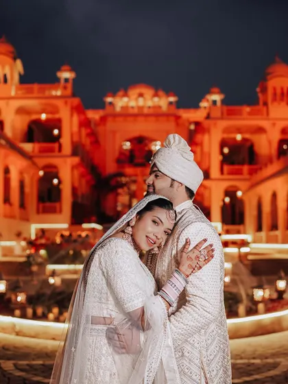 An intimate embrace against the beautifully lit facade of the Rajasthali Resort at night, a perfect blend of romance and architectural beauty.