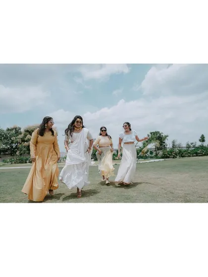 The bride and her bridesmaids running joyfully across a lawn during the Haldi festivities.