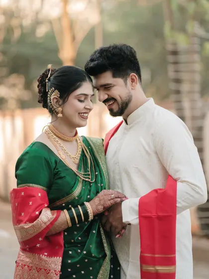 A joyful, candid moment between the couple, highlighting the vibrant colors and intricate details of their traditional Maharashtrian engagement outfits.