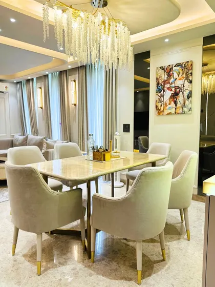 A beautifully set dining table under a cascading crystal chandelier. The mirrored wall behind reflects the light and adds depth to the room.