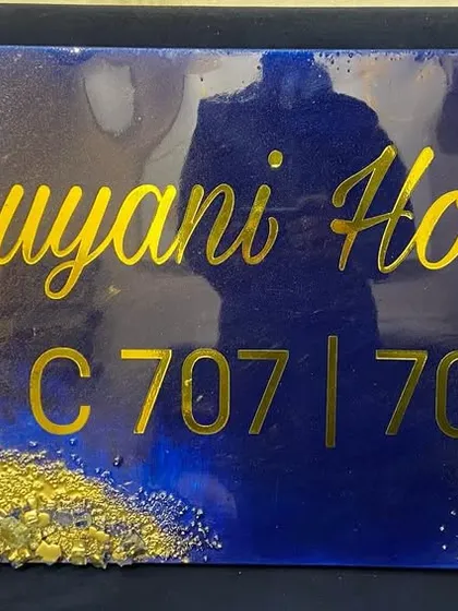 A close-up of the 'Luyani House' nameplate, showing the artist's reflection, which gives a sense of scale.