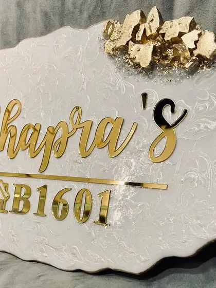 The white and gold 'Chhapra's' nameplate, showcasing a clean, modern design with elegant script and gold leaf accents.