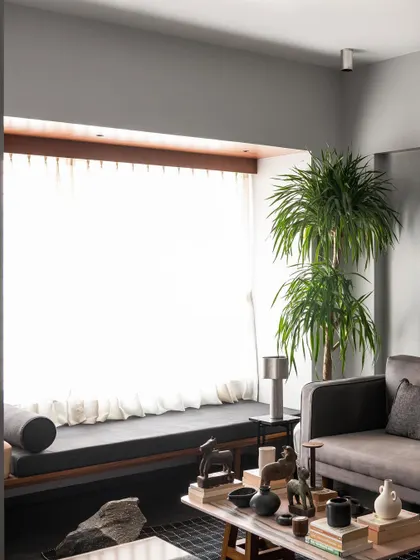 A view of the living room highlighting the window seat I designed. It provides a long, comfortable perch to enjoy the bright light from the large window, with the main seating area arranged for conversation.