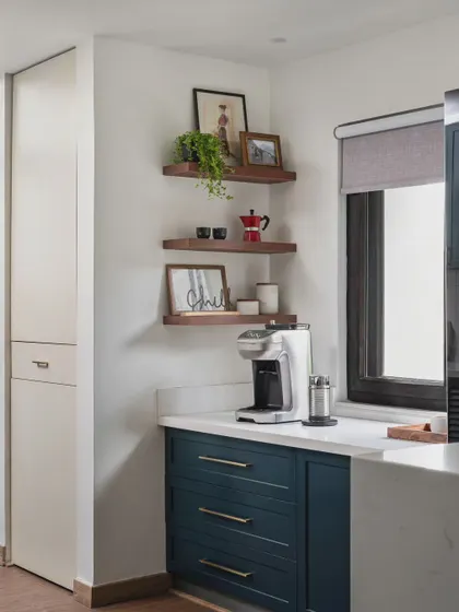 Details matter, especially in a kitchen. This little coffee corner with open shelving provides a designated spot for the coffee machine and mugs, keeping the main countertops clutter-free. The shelves are perfect for adding a personal touch with plants and photos.