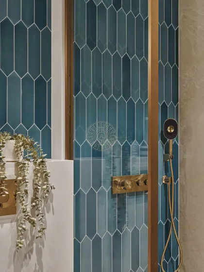 A close-up of the shower area, showcasing the rich blue picket tiles and brass fixtures. Even in a small space, material and color choices can make a big impact.