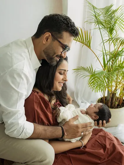 A lifestyle family portrait. Using natural light and simple props like a houseplant, we create a relaxed and authentic setting for your first family photos.