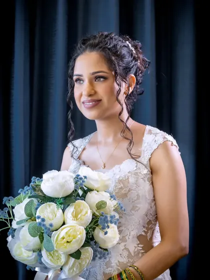 A beautiful portrait of the curly-haired bride. Her hair is styled in a lovely updo, and her makeup is soft, radiant, and flawless.