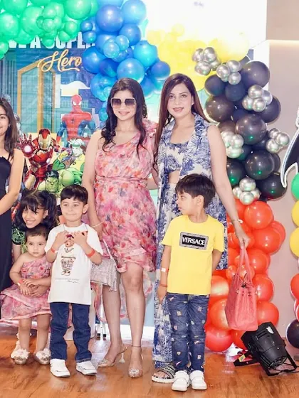 A group of friends and family gather for a photo at a fun-filled superhero birthday bash.