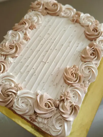 A large rectangular sheet cake decorated with an elegant border of piped rosettes.