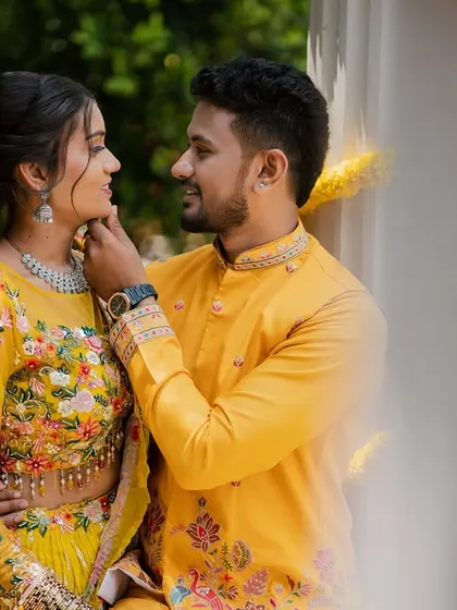 A close-up filled with tenderness during their Haldi ceremony. The vibrant yellow outfits and marigold flowers create a scene bursting with color and happiness.
