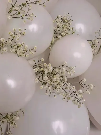 Beauty in simplicity. This close-up shows how adding delicate sprigs of baby's breath to simple white balloons can elevate the decor, adding a touch of natural elegance.