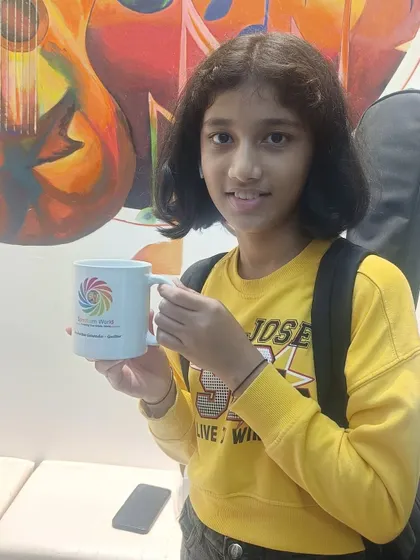 The student holds up her Spectrum World mug, a small gift to commemorate her achievement. We love celebrating our students' success stories.