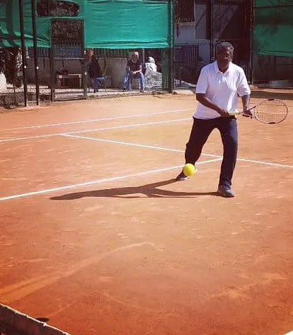 An adult player connects with a low ball during a competitive match in the Open Tournament.