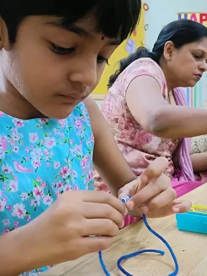 Another camper carefully works on her bracelet, choosing her beads and threading them onto the string. It is a calming and rewarding activity.