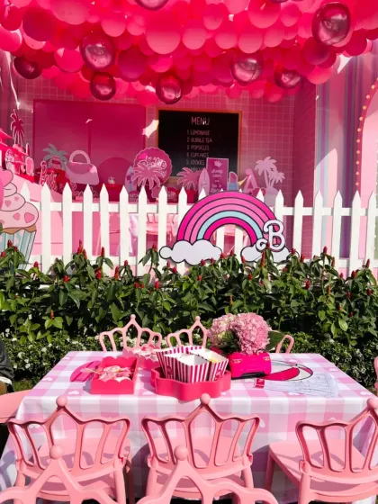 A view of the Barbie-themed party setup, complete with a rainbow, pink picket fence, and custom table settings. Every detail was designed to create a magical atmosphere.