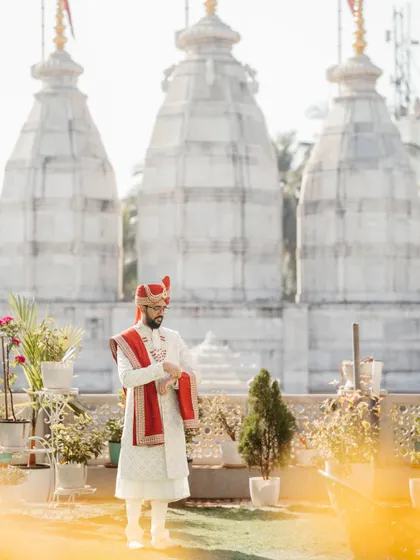 The groom in a moment of quiet reflection, with the traditional temple architecture in the background. This portrait is a beautiful blend of tradition and personal contemplation.
