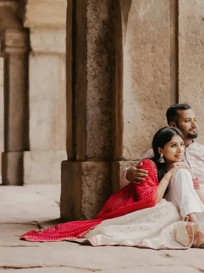 A quiet, intimate moment as a couple sits together against ancient stone pillars. The soft light and their relaxed pose convey a sense of comfort and timeless love during their heritage photoshoot.